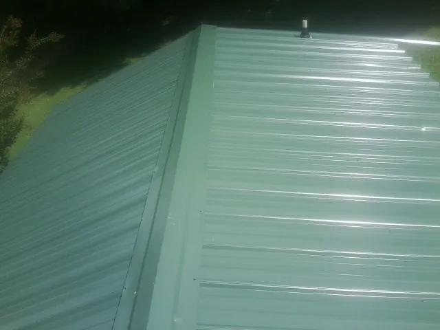 New green metal panels meeting at the ridge of a roof — Flat Roof Repair work by our crew in Letha