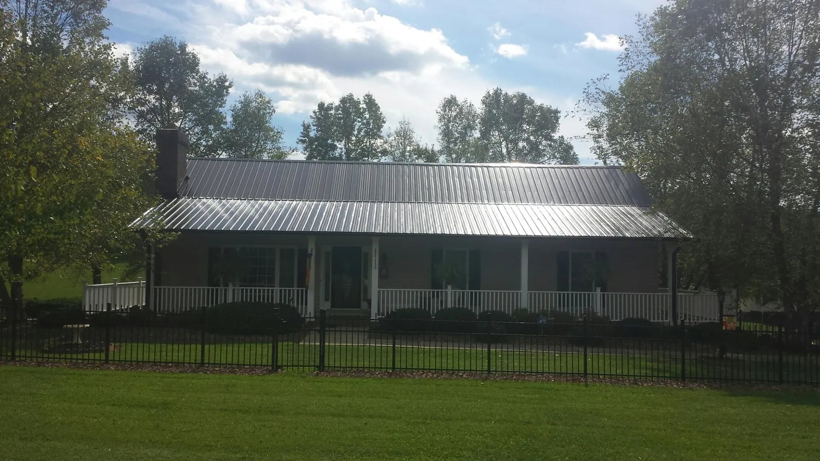 Gray metal roof on a brick ranch with a full width front porch — Gutter Guard Installation work by our crew in Letha