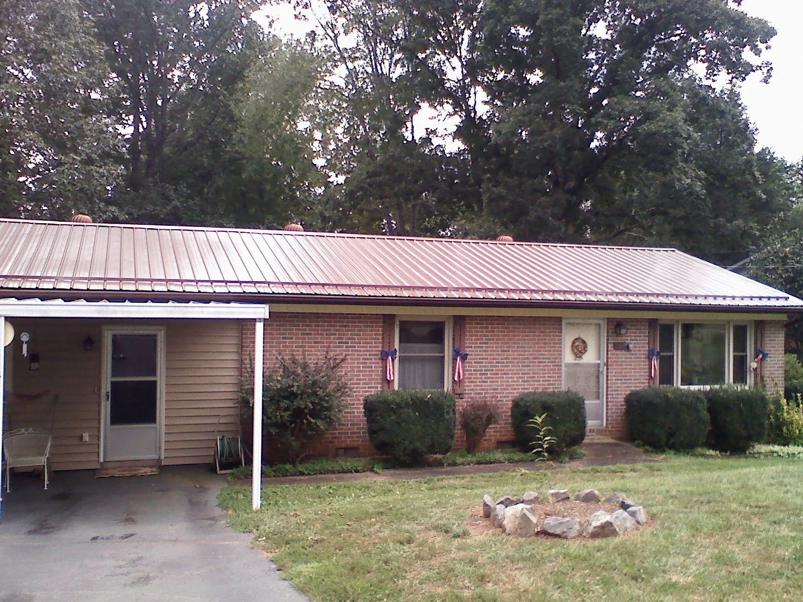 Bronze metal roof and carport on a brick ranch home — Roof Repair work by our crew in Letha