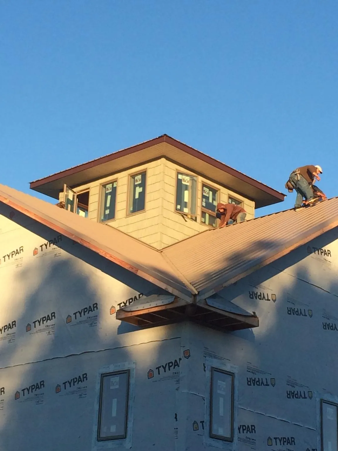 Roofers working around a rooftop cupola on a new metal roof at sunset — Roof Waterproofing in Letha by Roofing Brothers